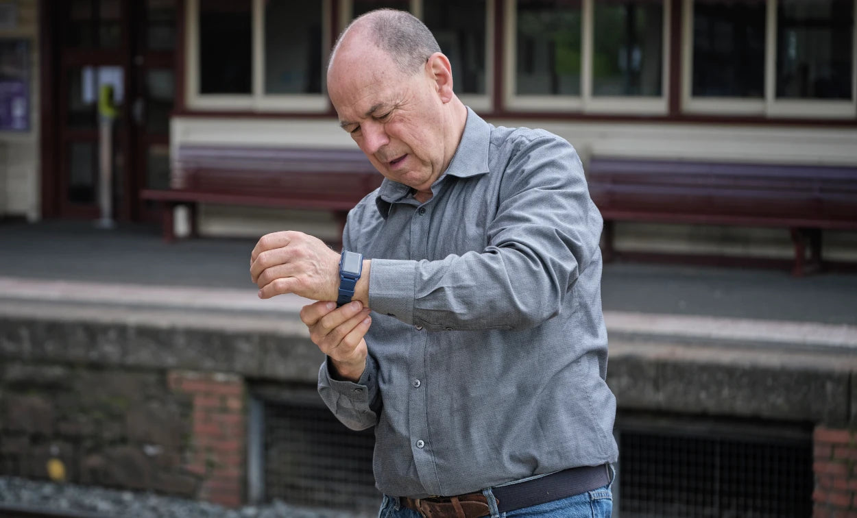 Man adjusting his watch on a train platform